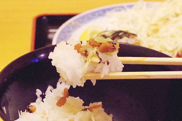 箸で持ち上げた納豆を乗せたご飯