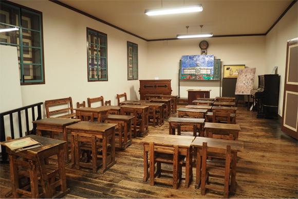 木製の机と椅子が並ぶ小さな教室