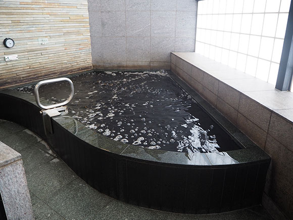 扇のような形をした黒湯の浴槽