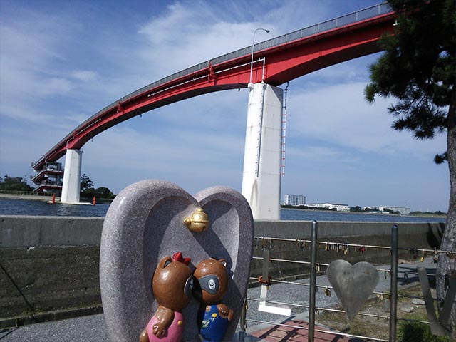狸の像と大きな赤い橋