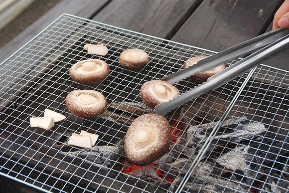 トングでしいたけを網に並べる様子