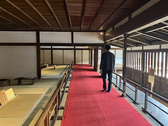 赤い毛氈の上を歩く男性