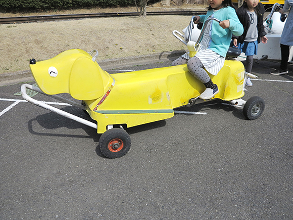 黄色い犬型自転車に乗る子ども