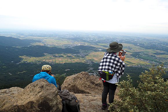 山頂から見下ろす景色と写真を撮る人