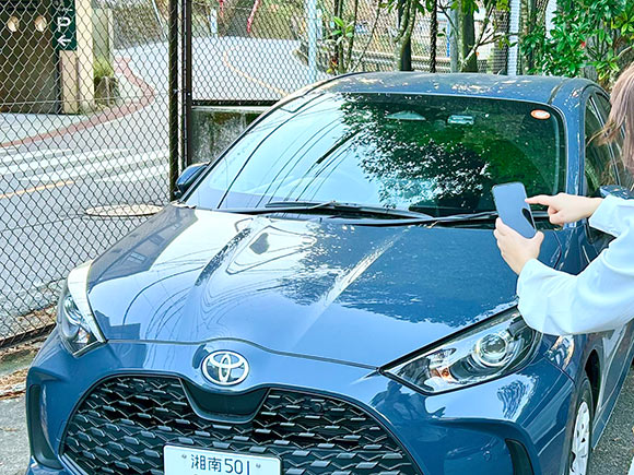 クルマにスマホをかざす女性