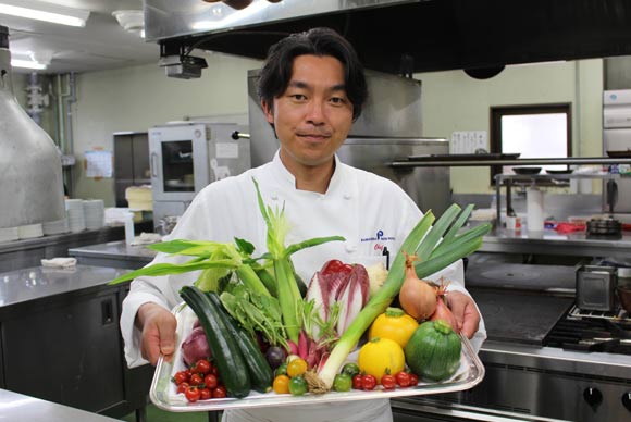 新鮮野菜を見せる西田シェフ