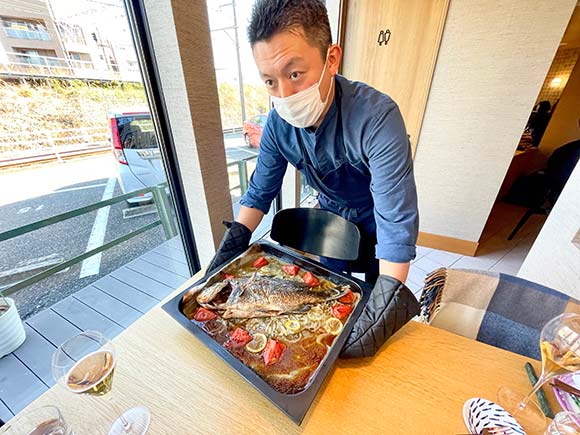 焼きたての魚を見せるシェフ