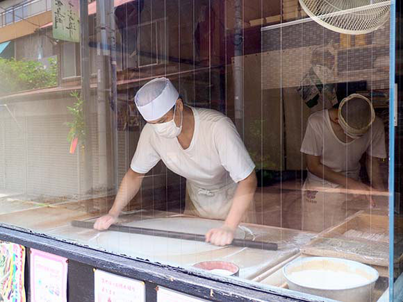 店頭でそばを打つ男性