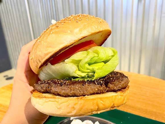 厚みのあるハンバーガーを片手で持つ様子