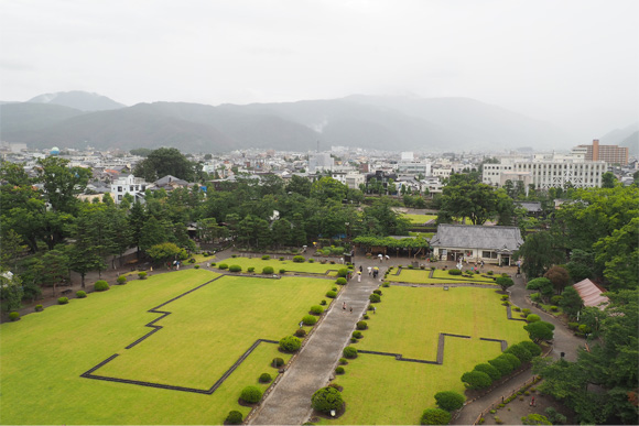 広い芝生の向こうに街並みと山々