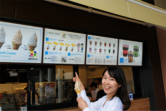 店頭のメニューを指さす女性