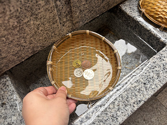 水につけた丸いザルと小銭