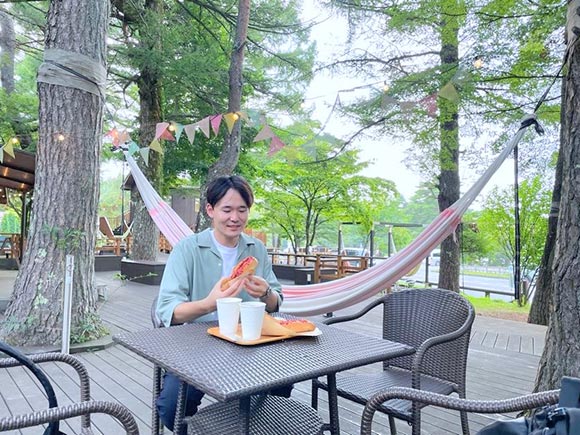 屋外テラスでホットドッグを食べる男性