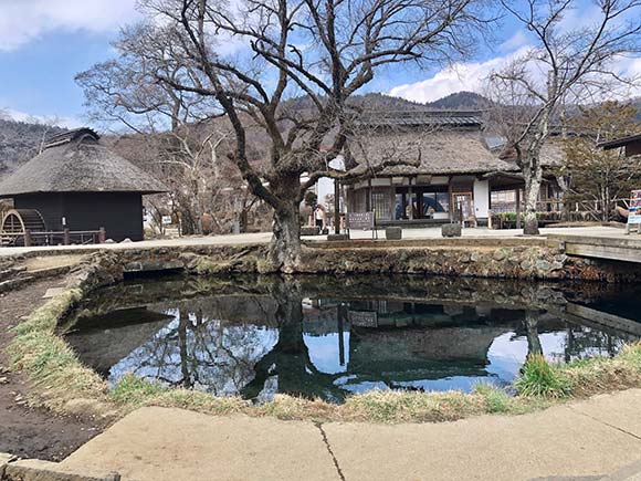 茅葺屋根の建物に囲まれた池